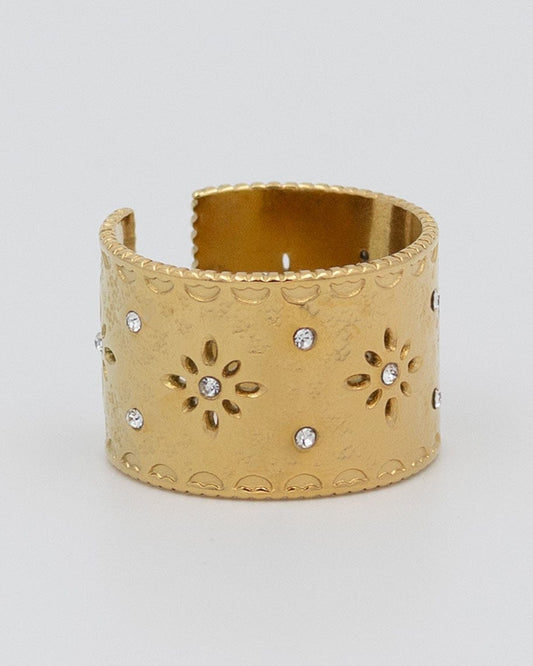 anillo ancho dorado con flores caladas y circonitas pequeñas con un borde irregular